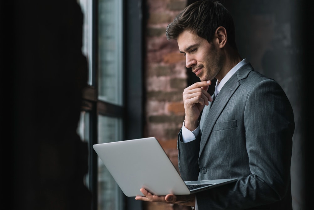 thoughtful-smart-young-businessman-looking-laptop